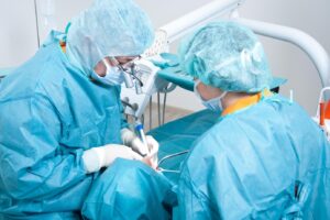 Zwei Zahnärzte in blauer Schutzkleidung bei einer Behandlung